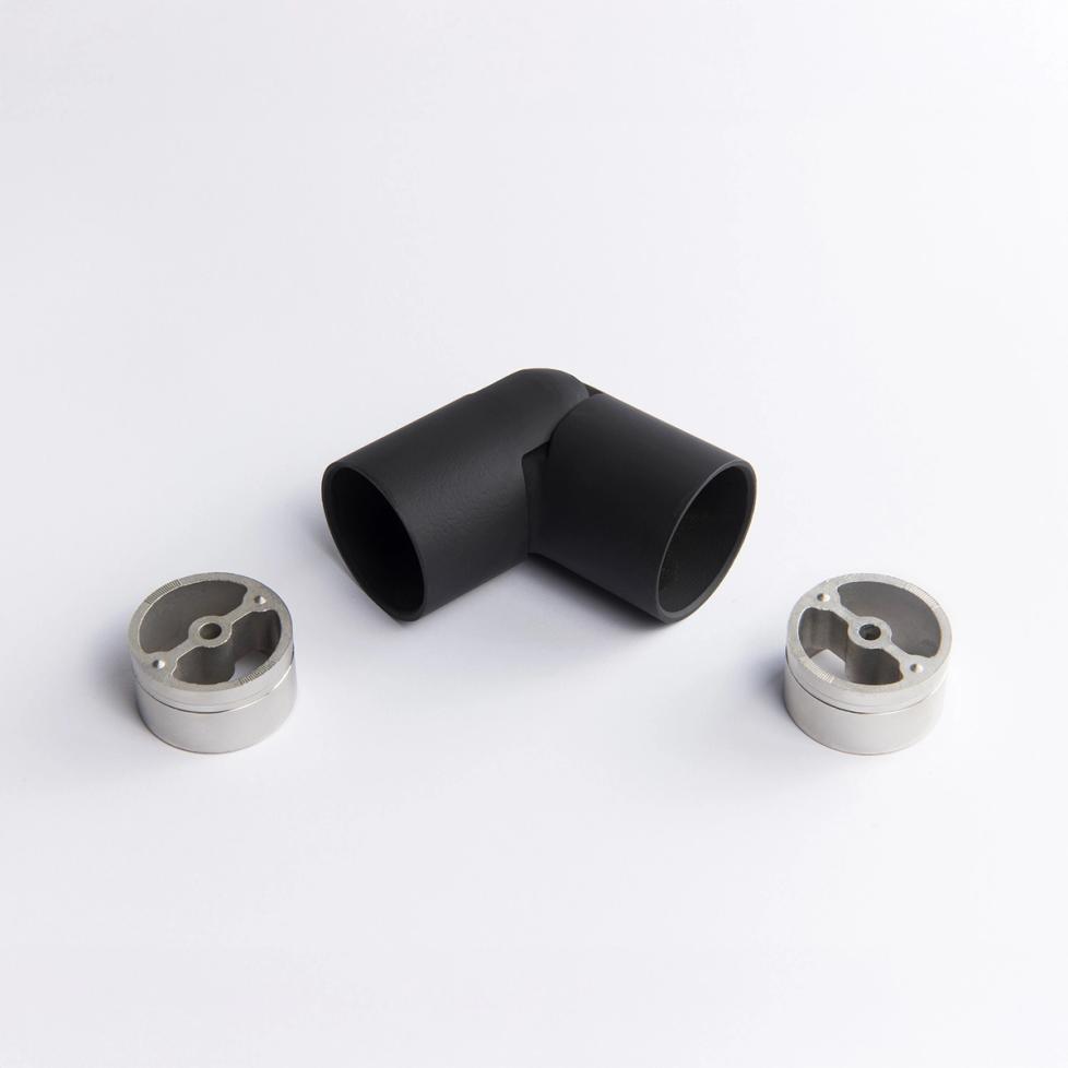 A flexible black metal tube connector positioned between two silver circular mounting inserts  43mm